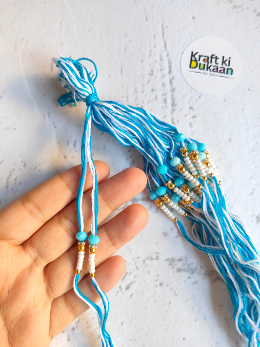 Blue rakhi thread with bead drops and knotted ends, held in hand