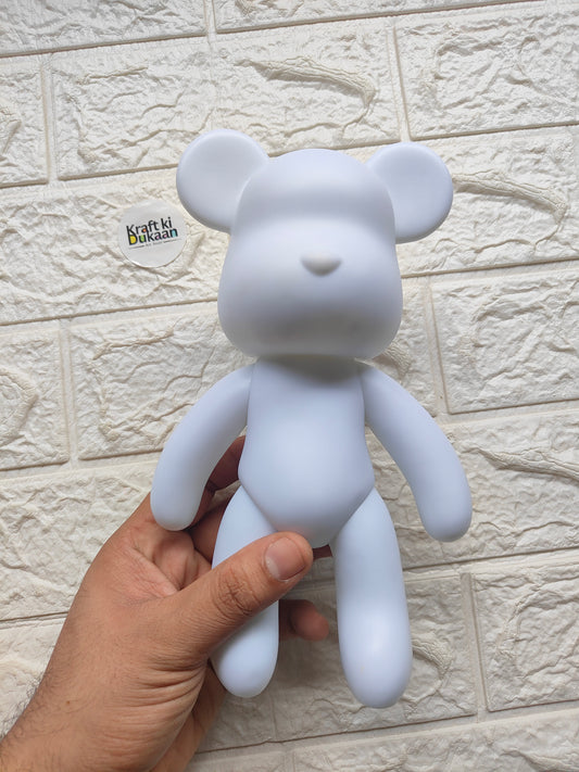 Light blue teddy bear figurine with closed eyes and small nose