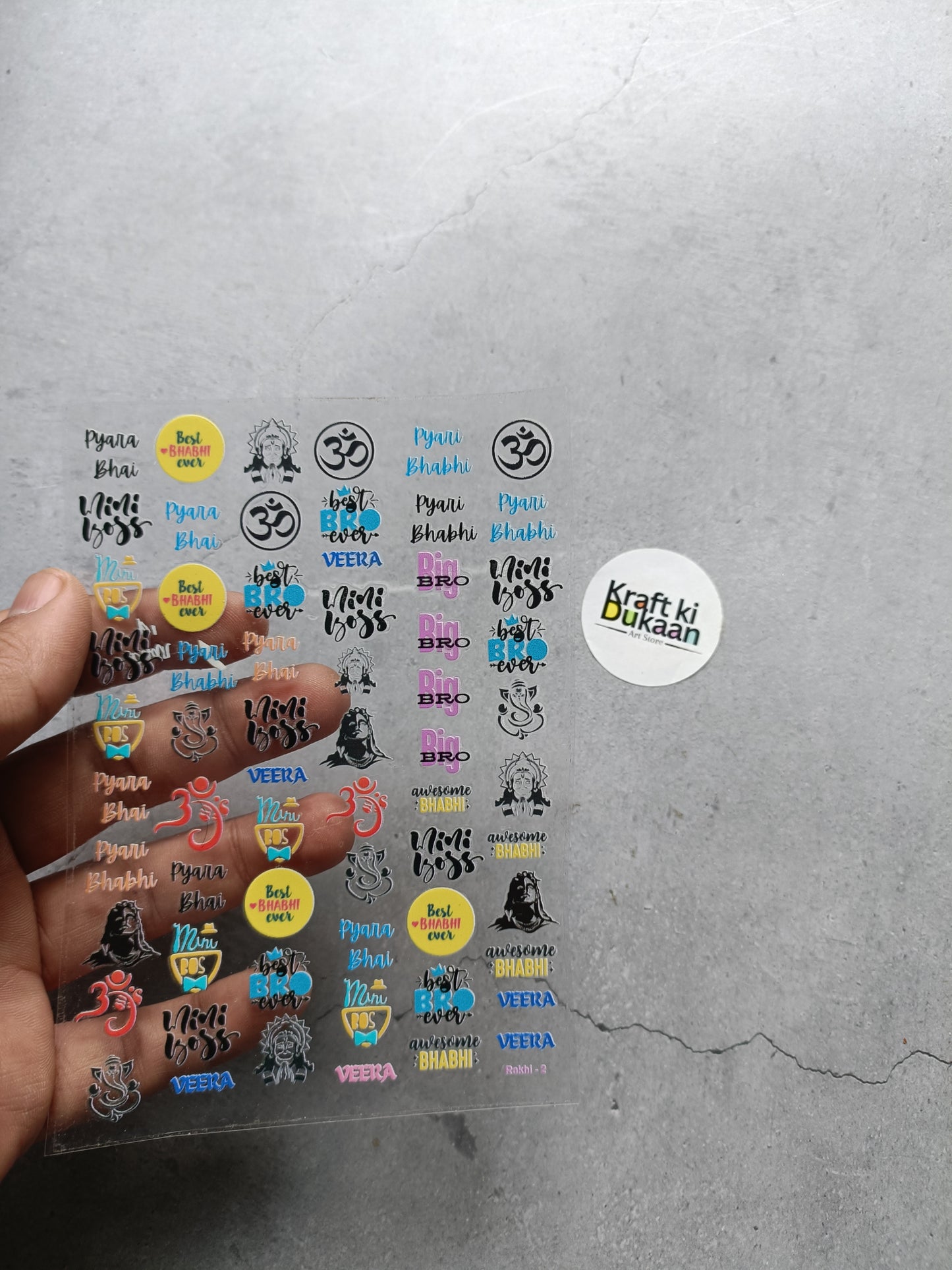 Peel-off sticker sheet held in hand, assorted UV DTF decals on clear backing