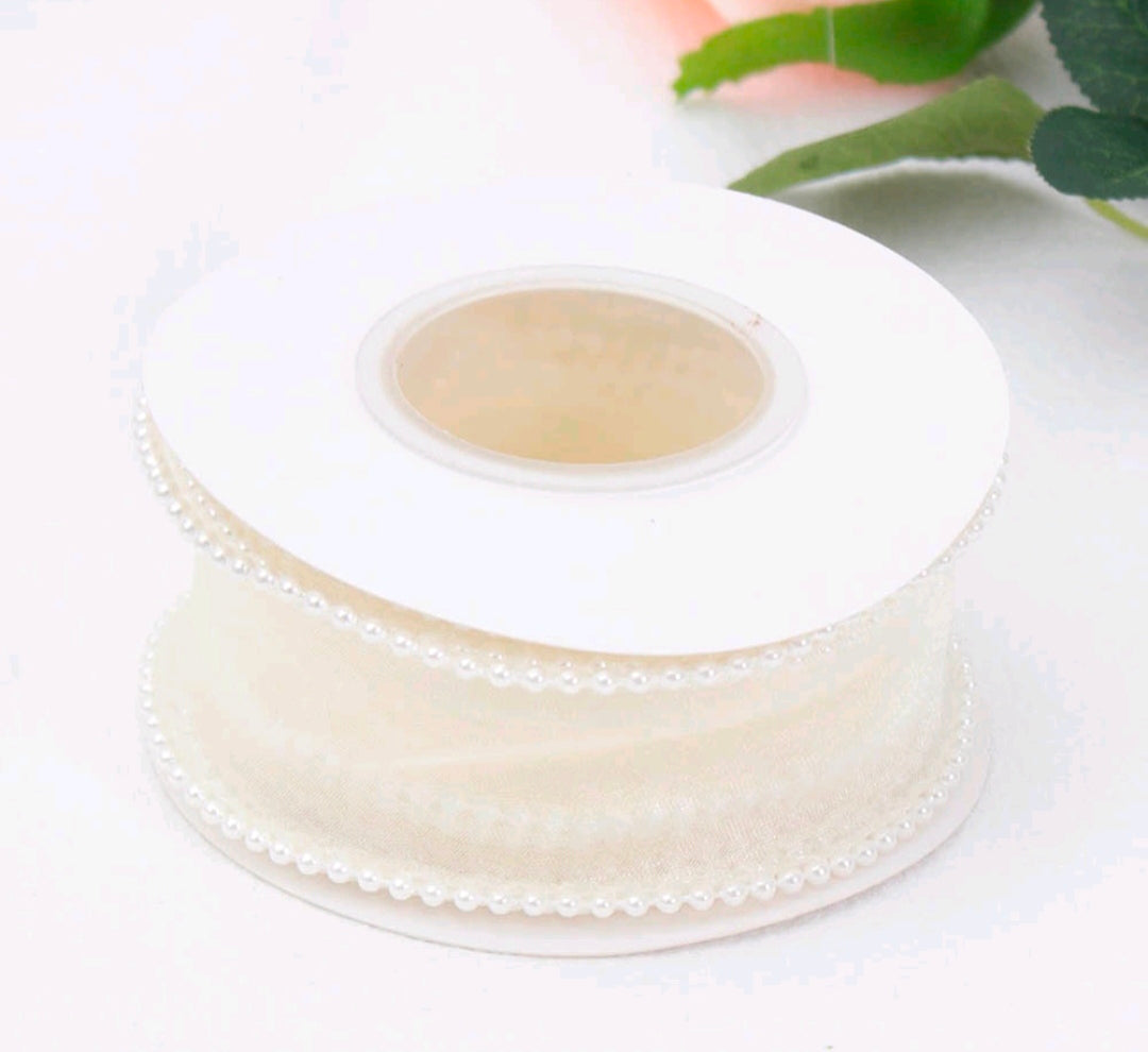 Off-white satin ribbon roll with pearl beaded edge trim, curved top view