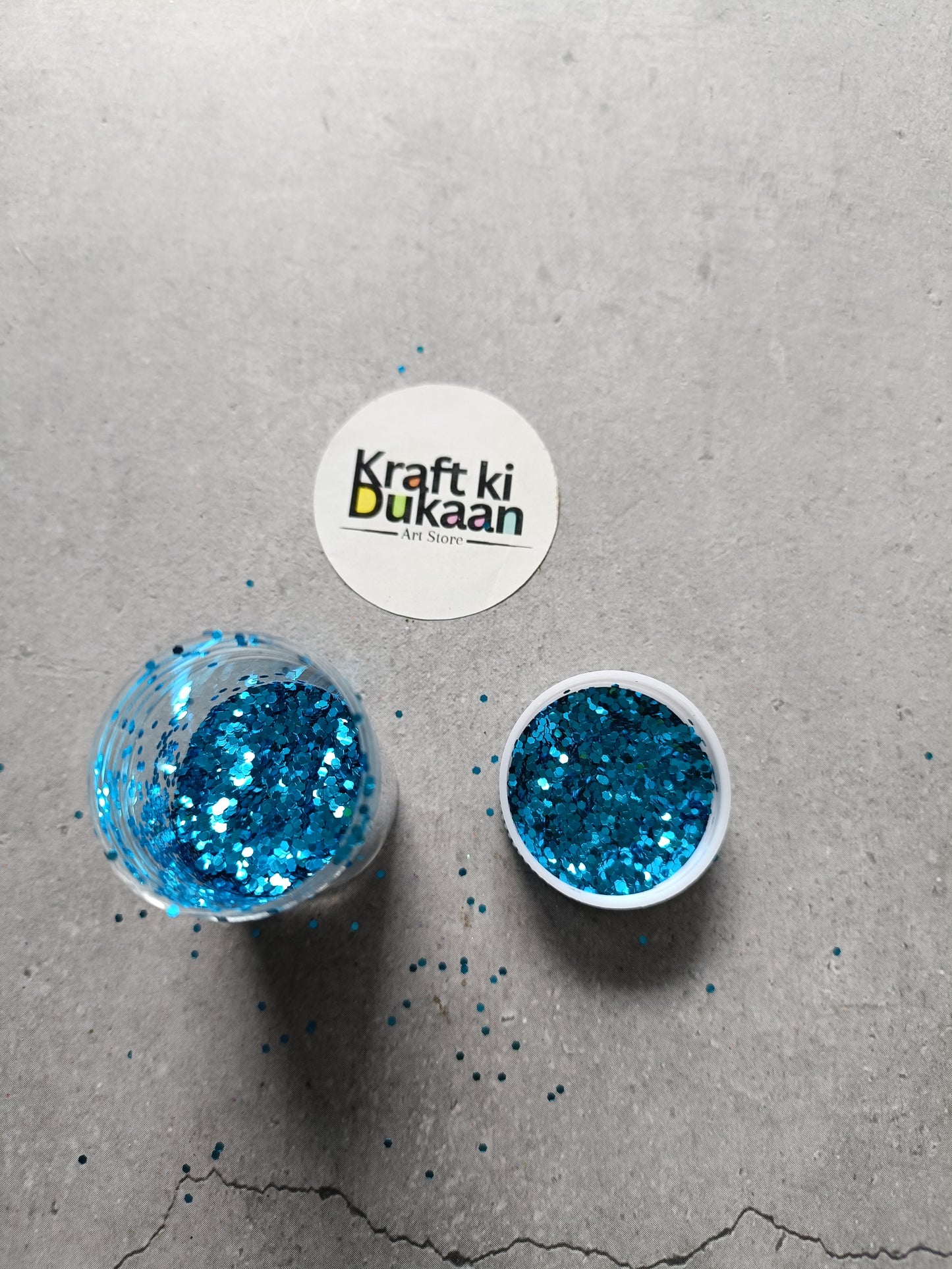 Hexagon-shaped glitter containers with blue glitter flakes, two round lids