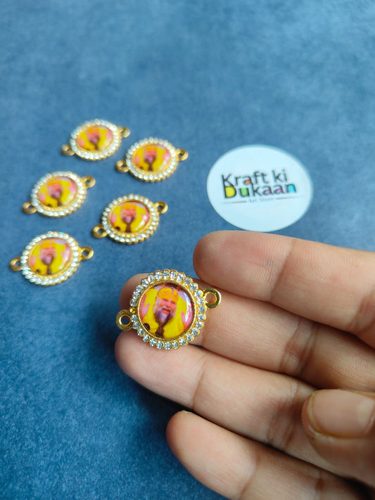 Gold-tone circular rakhi pendant charm with pink deity center and beaded border, in hand