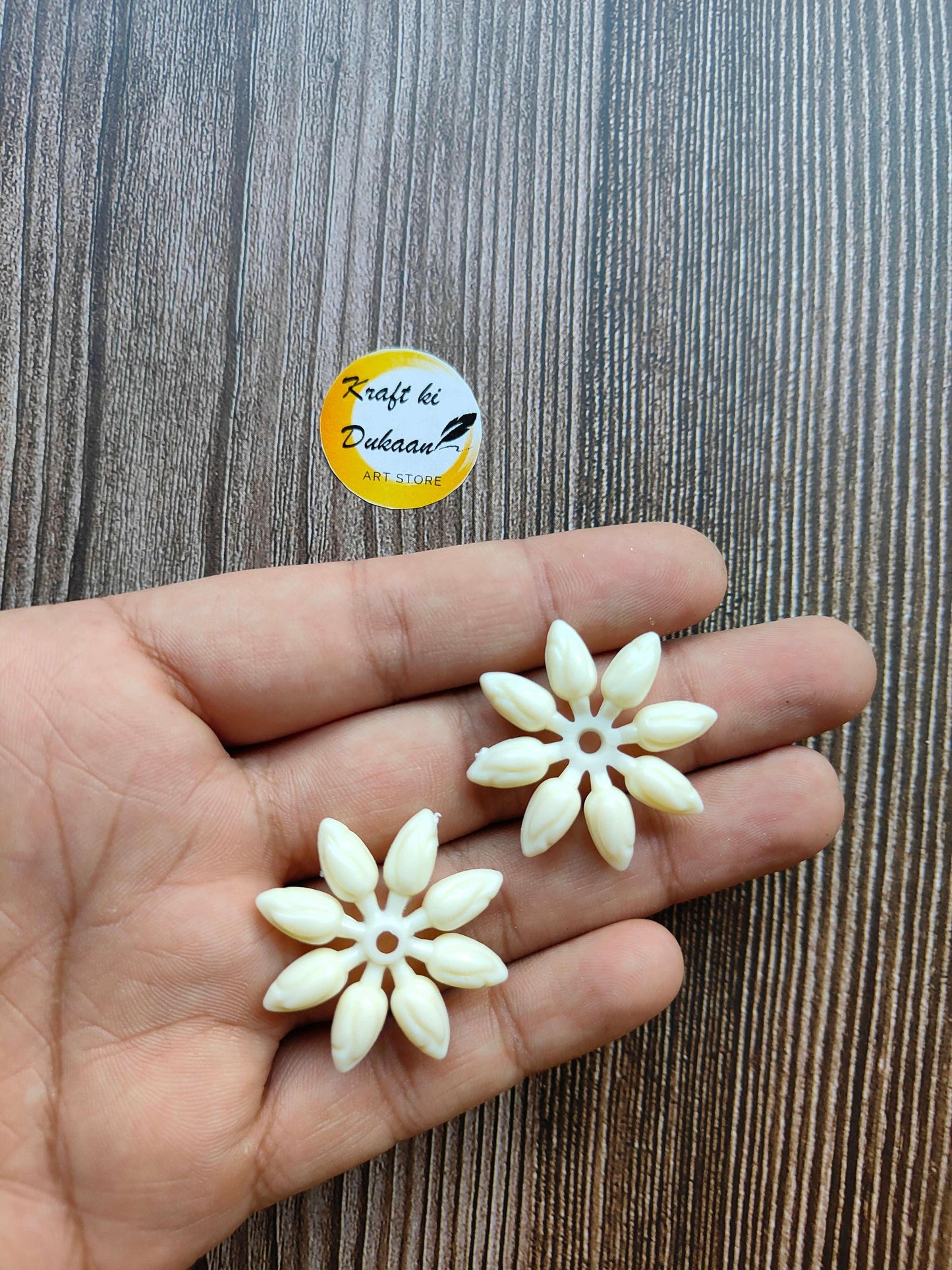 Two cream-white flower beads on palm, detailed petals and center