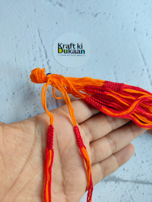 Rakhi dori threads in orange with red accents, held in hand