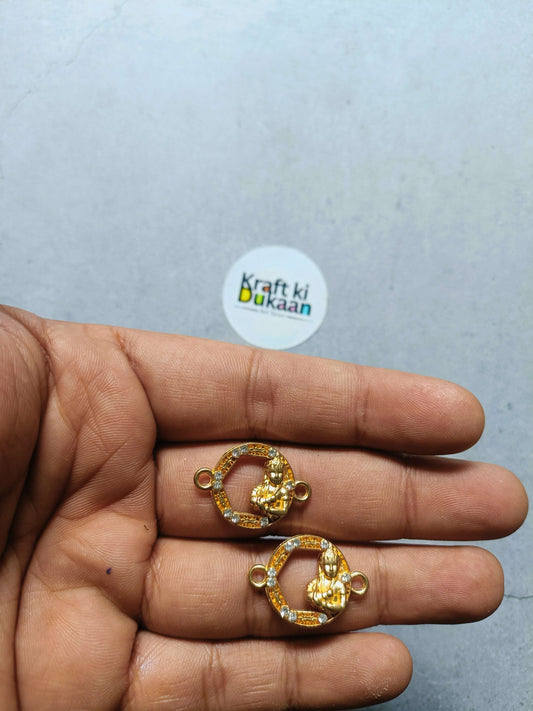 Round gold-toned rakhi bracelet charm on fingers, rhinestone bezel with side loops