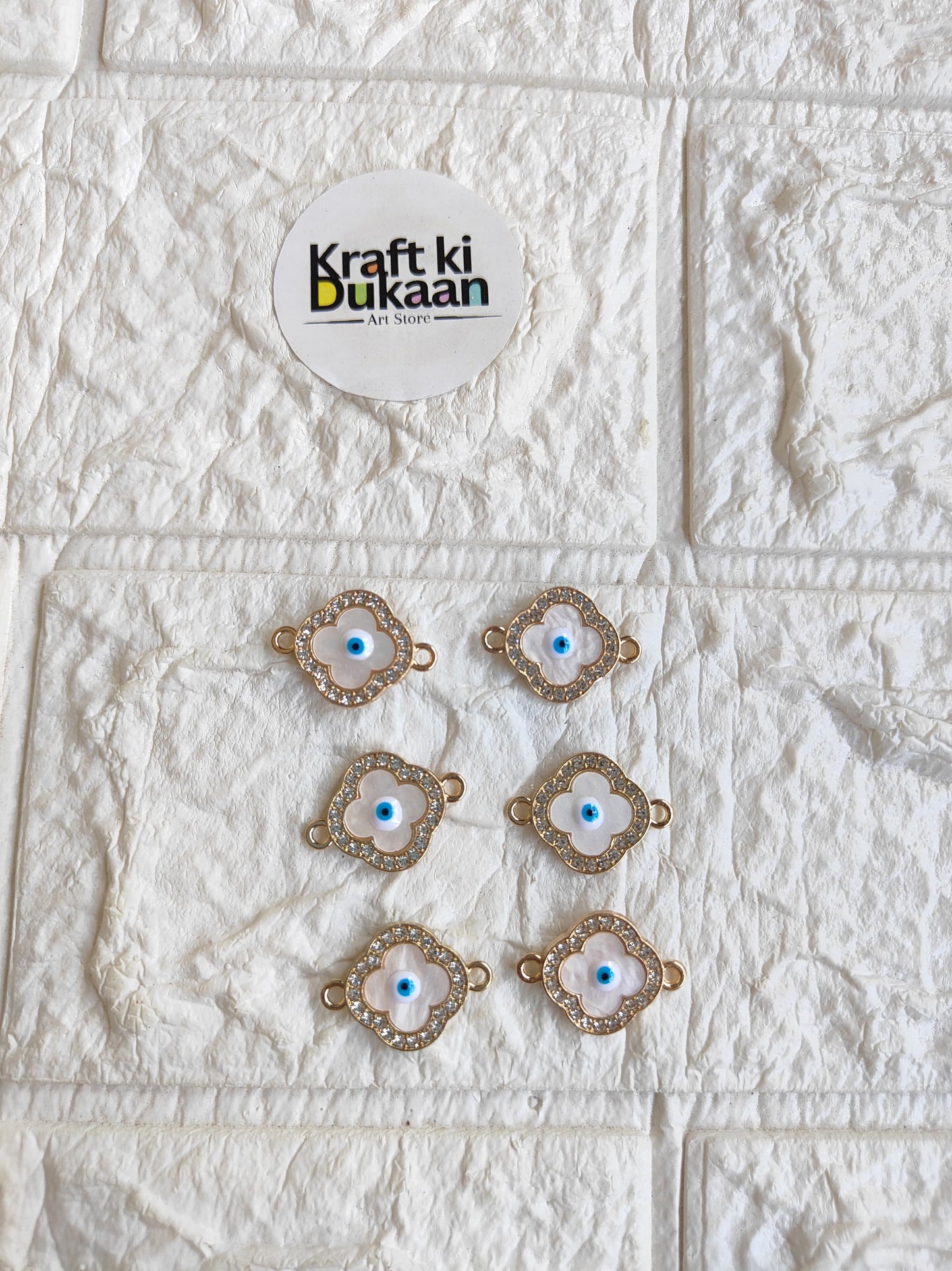 Gold-tone rakhi bracelet pendant set with blue evil-eye motifs, arranged on surface