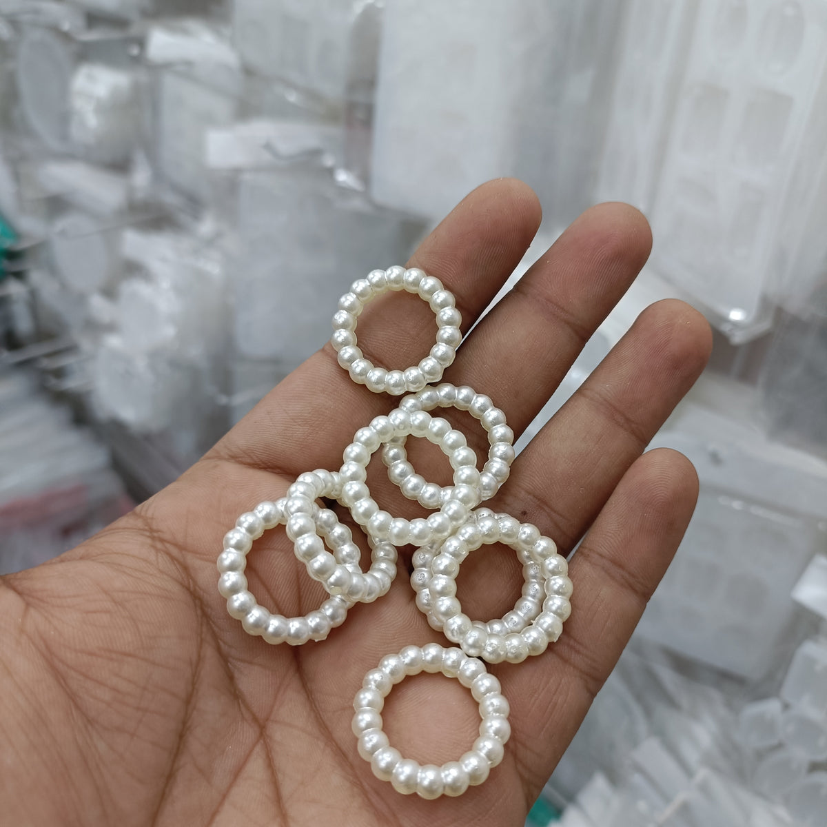 White pearl bead rings, round loop bands shown in hand (pack of 25)