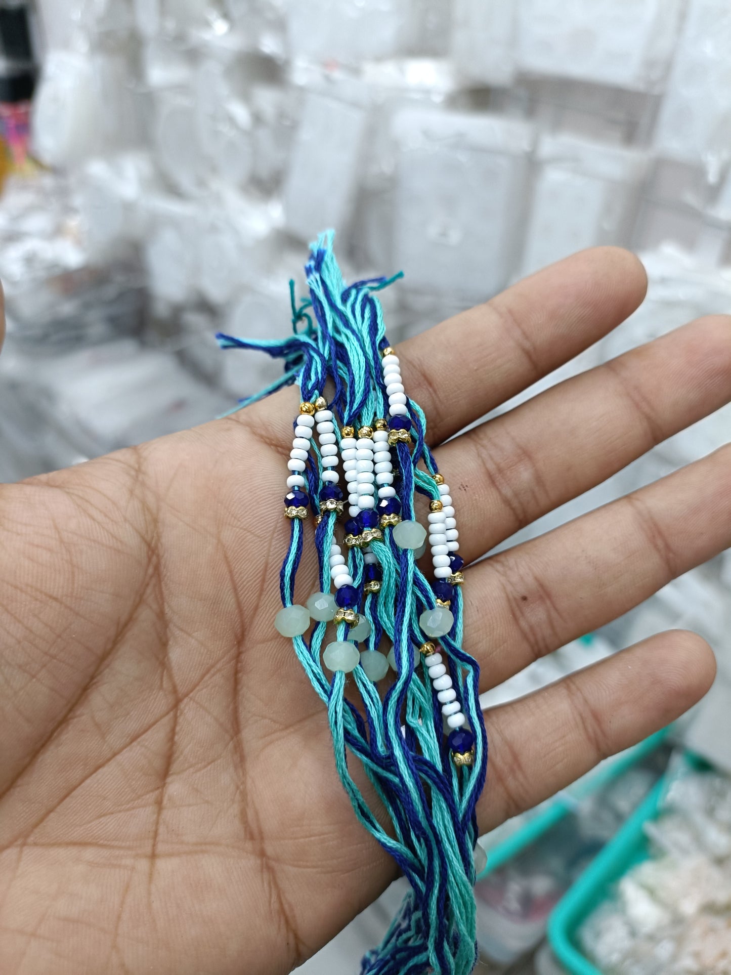 Blue beaded rakhi dori with white pearls and tassels, small charm accents