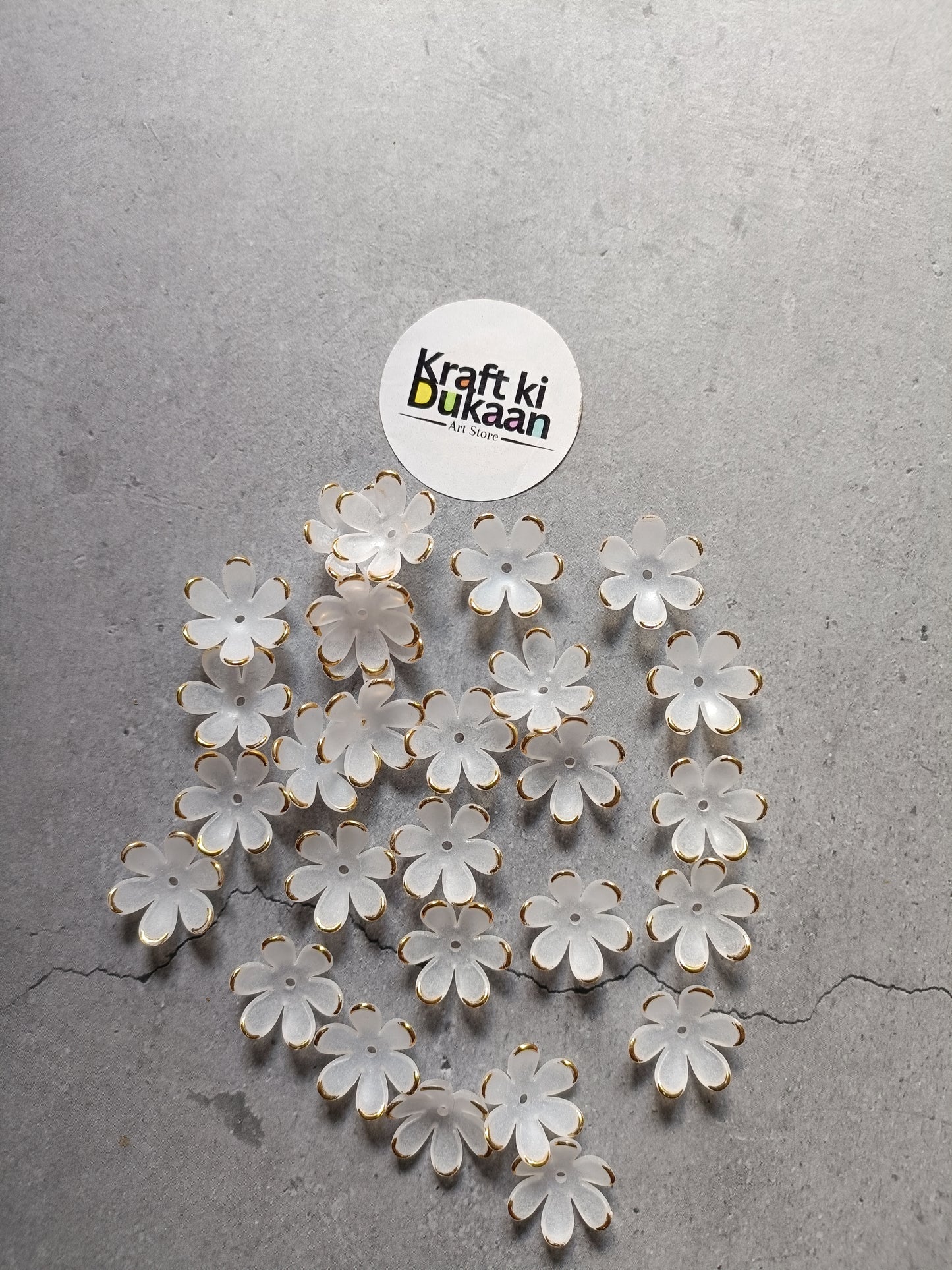 White flower-shaped beads scattered on surface, with gold-tone metal loops