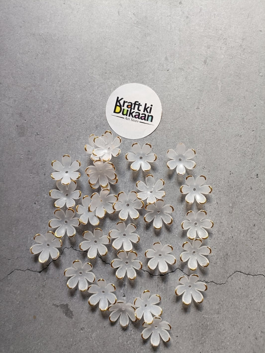 White flower-shaped beads scattered on surface, with gold-tone metal loops