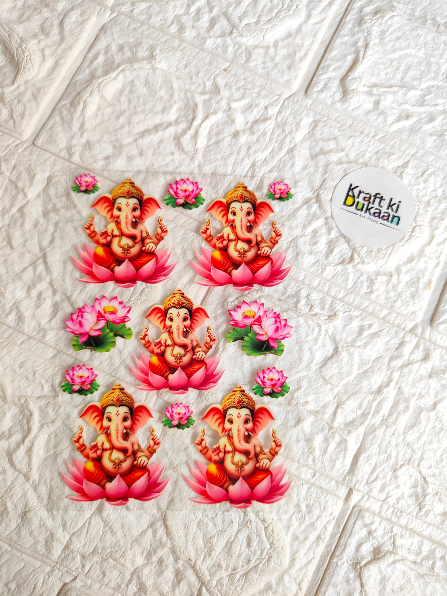 Peel-off sticker sheet with five orange Ganesha faces and pink flower decals