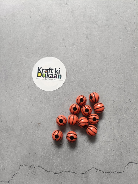 Rakhi bracelet bead set of orange striped beads with black spiral patterns, scattered