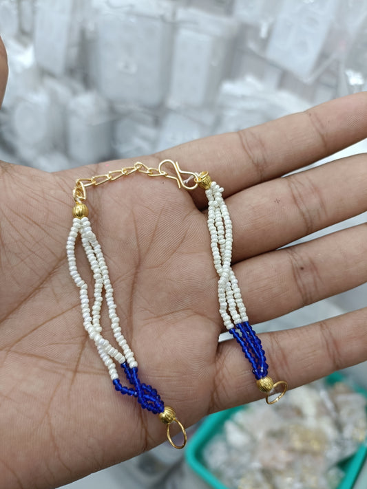 Rakhi bracelet chain with white bead strands, blue charm, and gold link clasp