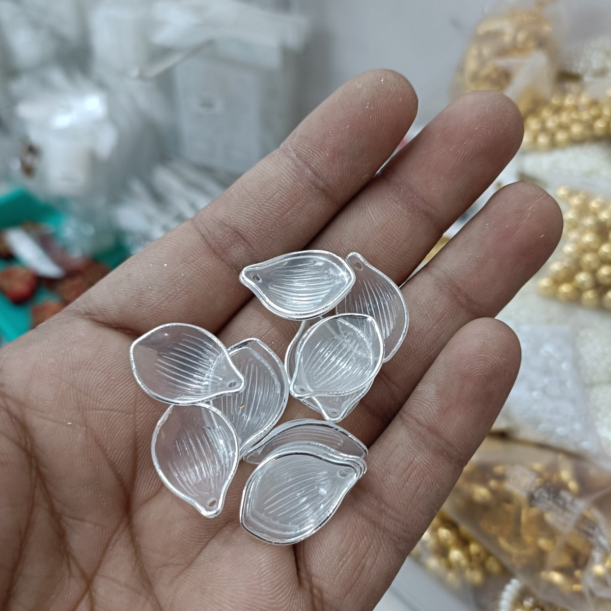 Silver-trim clear acrylic petal beads in hand, 50-pack, leaf-teardrop shape