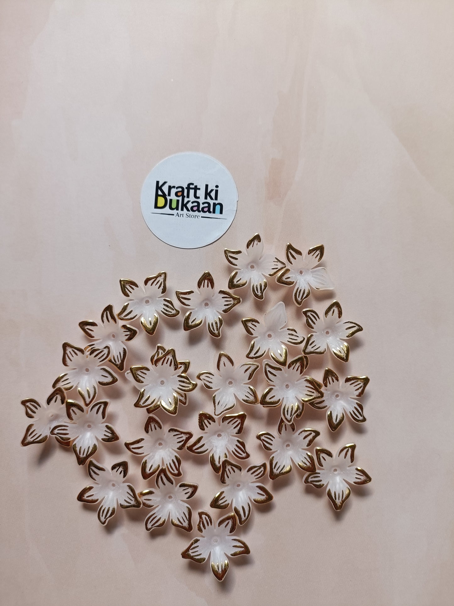 Flower bead charms, white flowers with gold outlines, scattered on surface