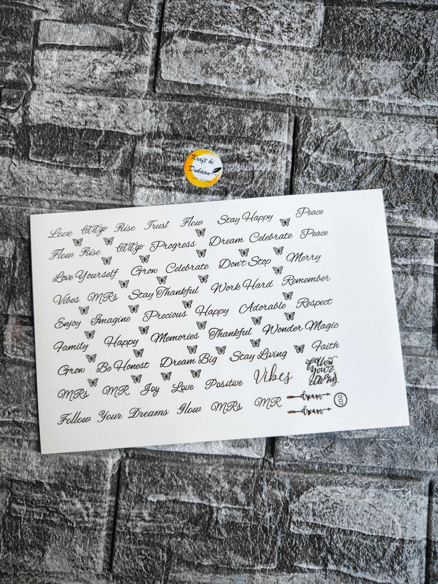 Gold embossed sticker sheet with many cursive word designs on white sheet