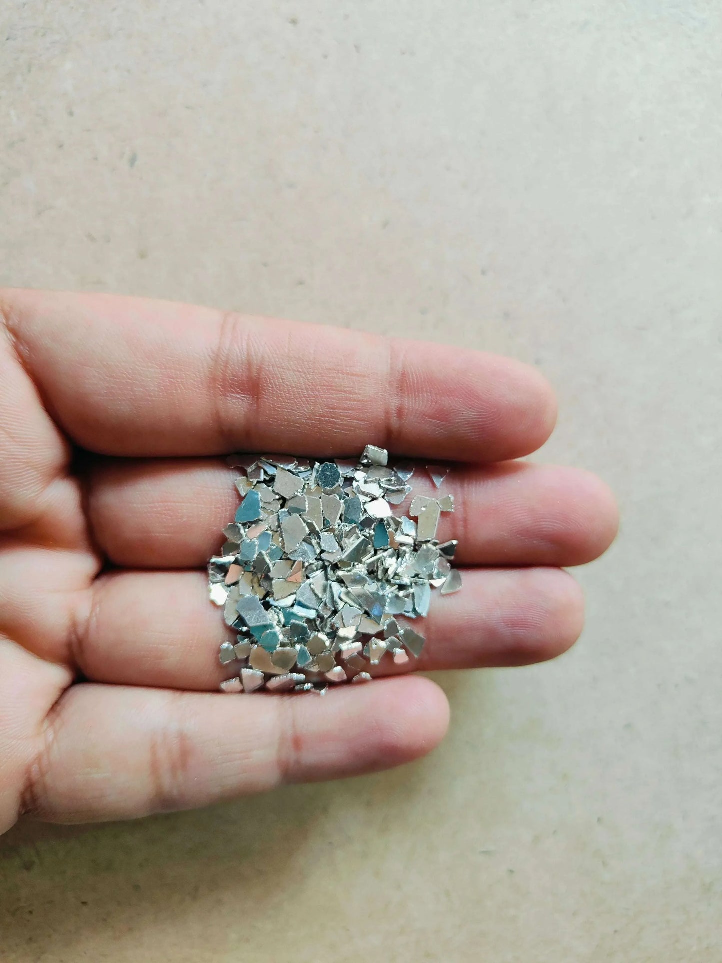 Silver crystal chips held in hand, small mirrored square fragments