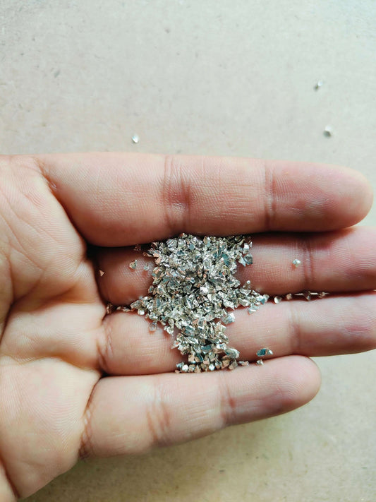 Hand holding shimmering silver granules for resin art, perfect for creative projects