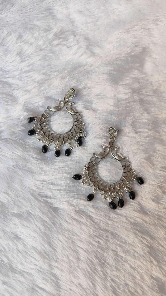 Pair of silver jhumka with circular center and ornate hoops, ending in black beads
