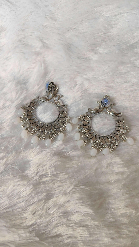 Pair of silver jhumka earrings, filigree edges, white beads and blue top.
