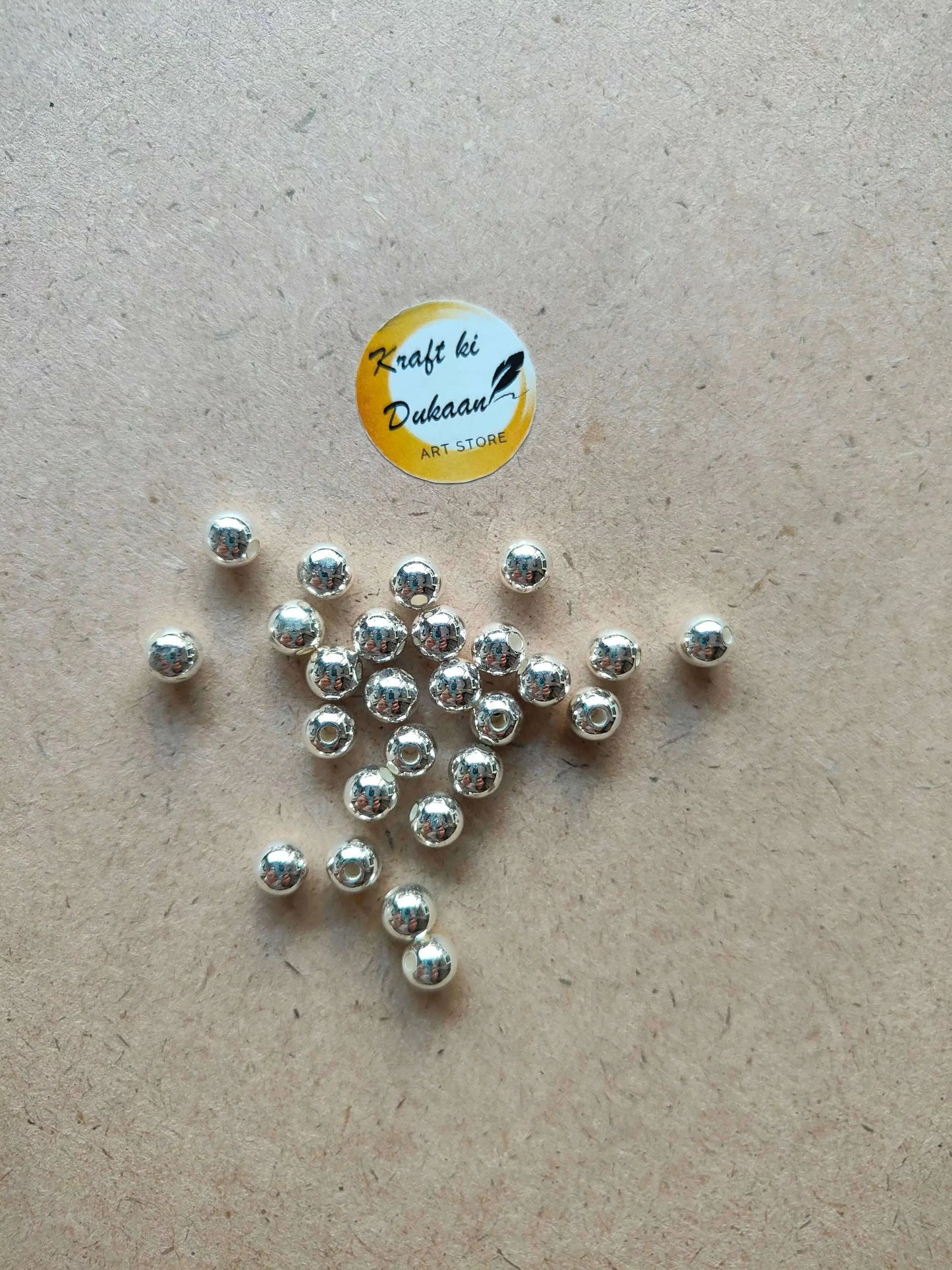 Silver pearl beads on light surface, round metal beads with center holes