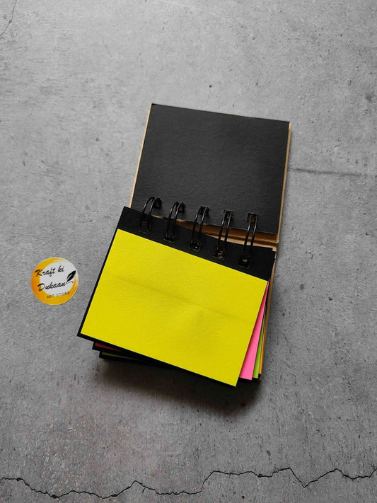 Spiral sticky note pad with bright yellow sticky sheets and black metal rings