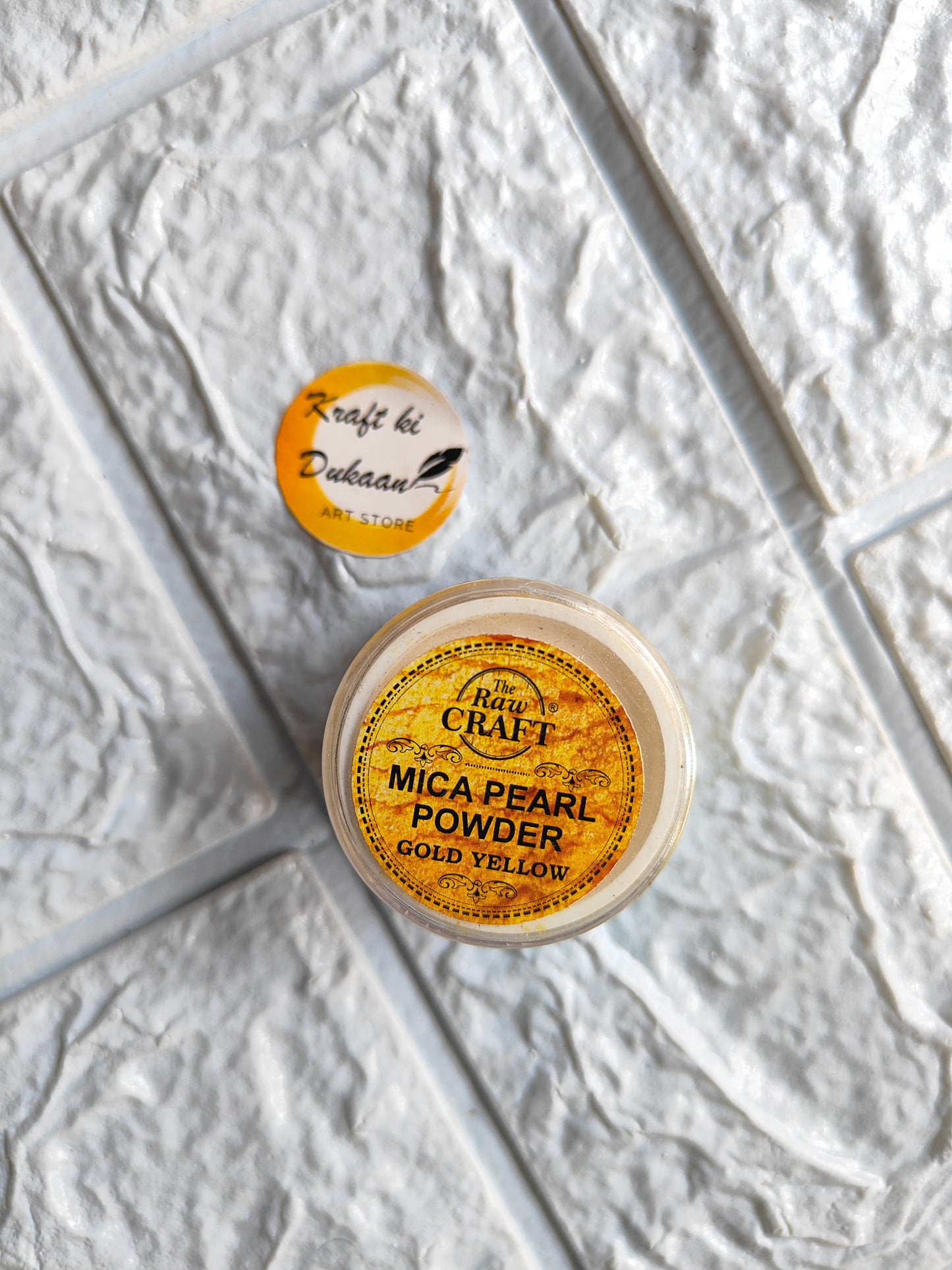 Kraft ki Dukaan gold yellow MICA pearl powder for resin in a small container on textured surface