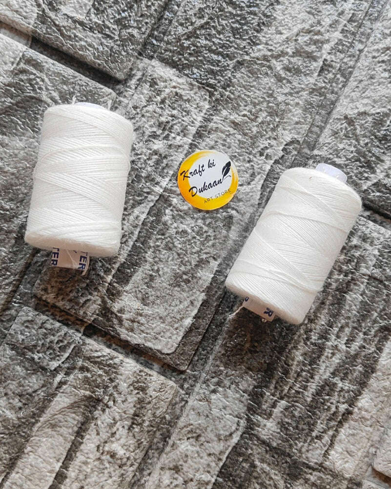 White thin yarn on two spools, fine twisted strands, light off-white thread