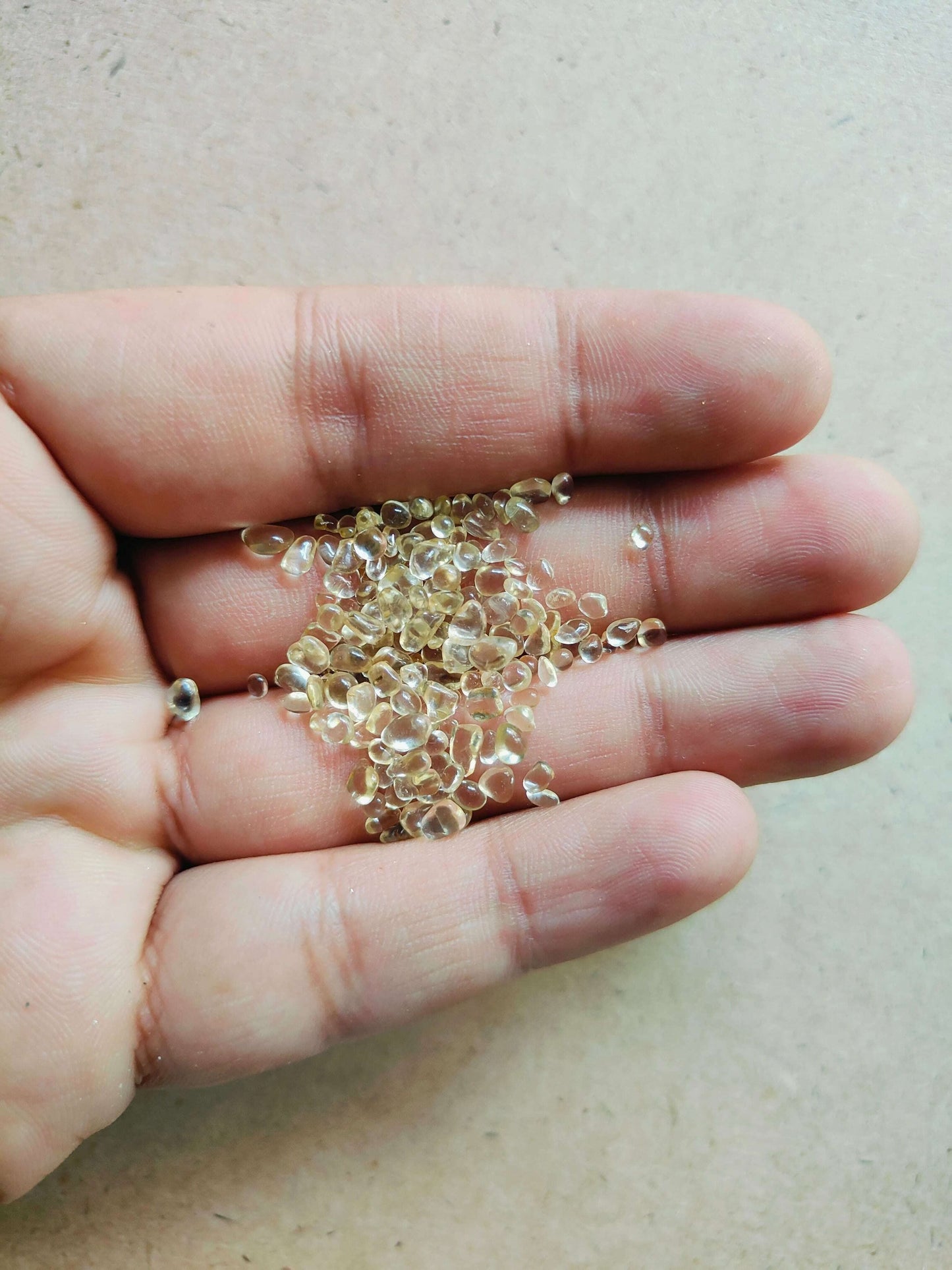 Hand holding yellow glass crystals for resin art, perfect for adding vibrant color and texture