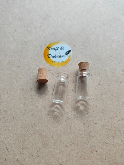 Two small glass bottles with cork stoppers on a textured surface