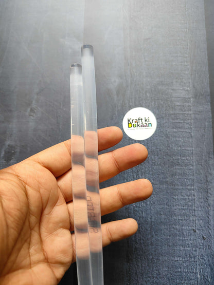 Pack of 2 hot melt glue sticks, clear translucent plastic, held in hand