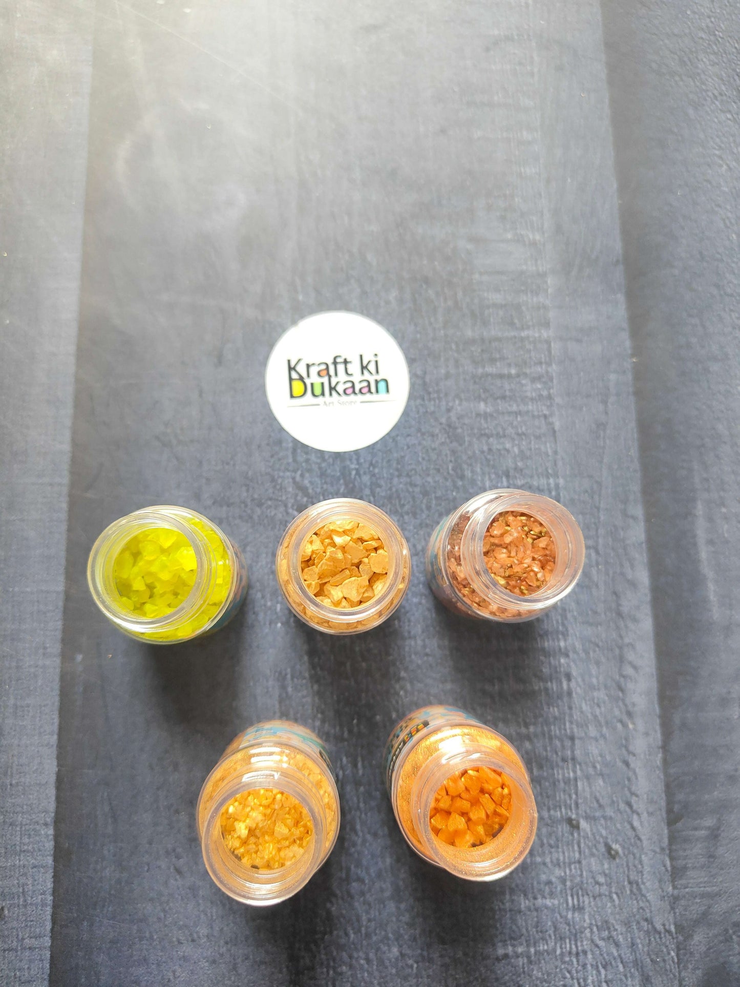 Five open jars of glass stone pieces in green, gold, orange and copper shades
