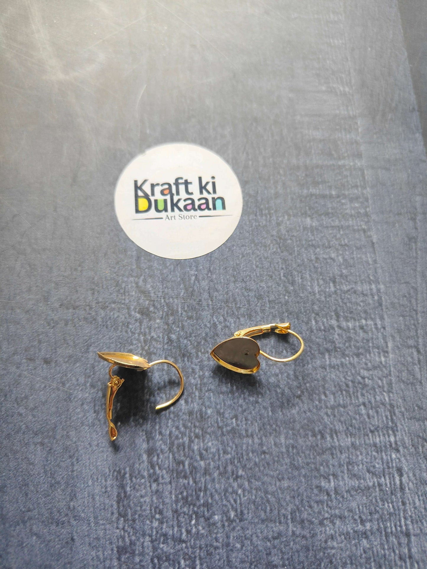 Gold heart earring bases with hinged open tops on fabric