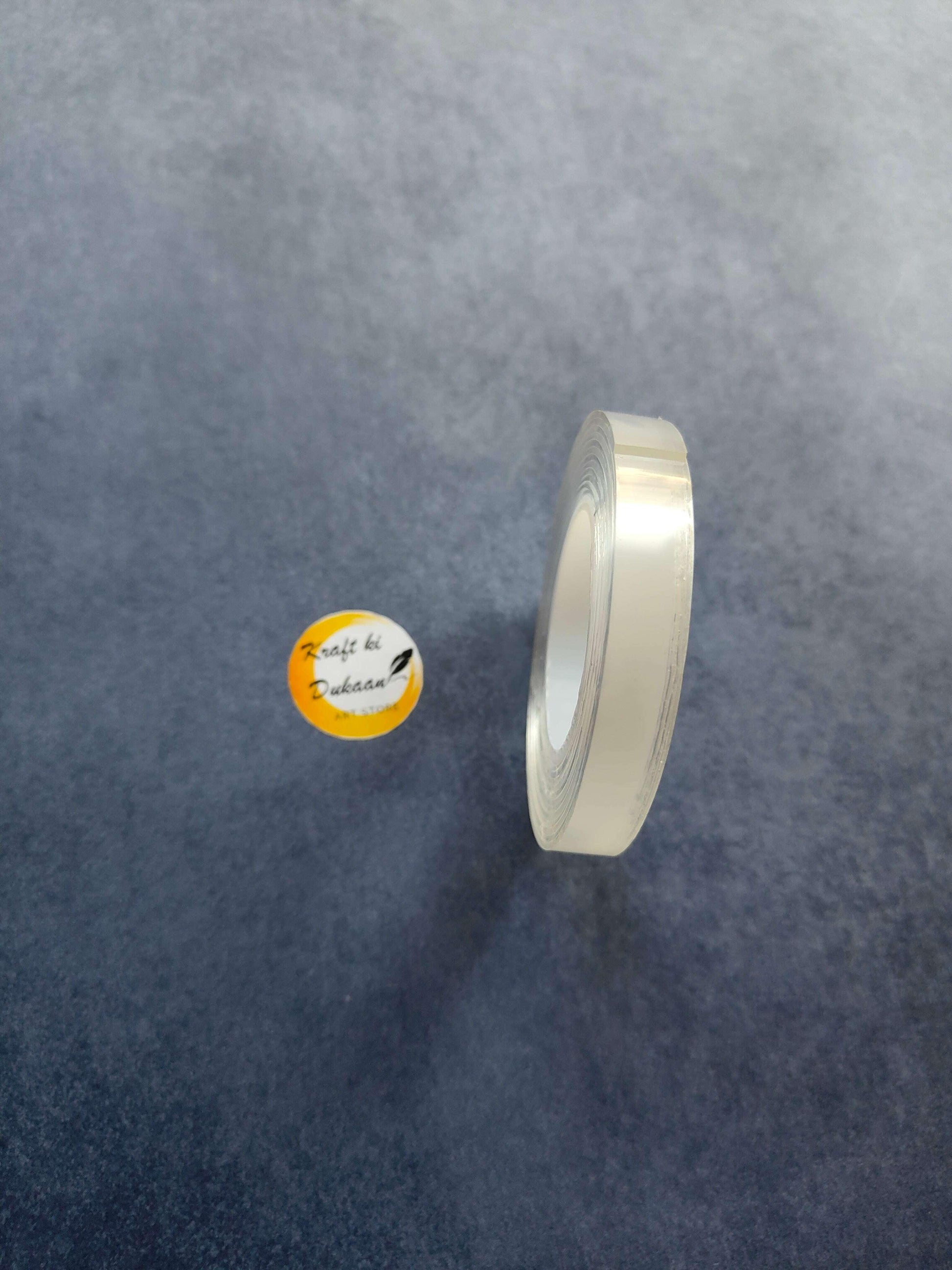 Clear double-sided tape roll with visible adhesive edge and inner core