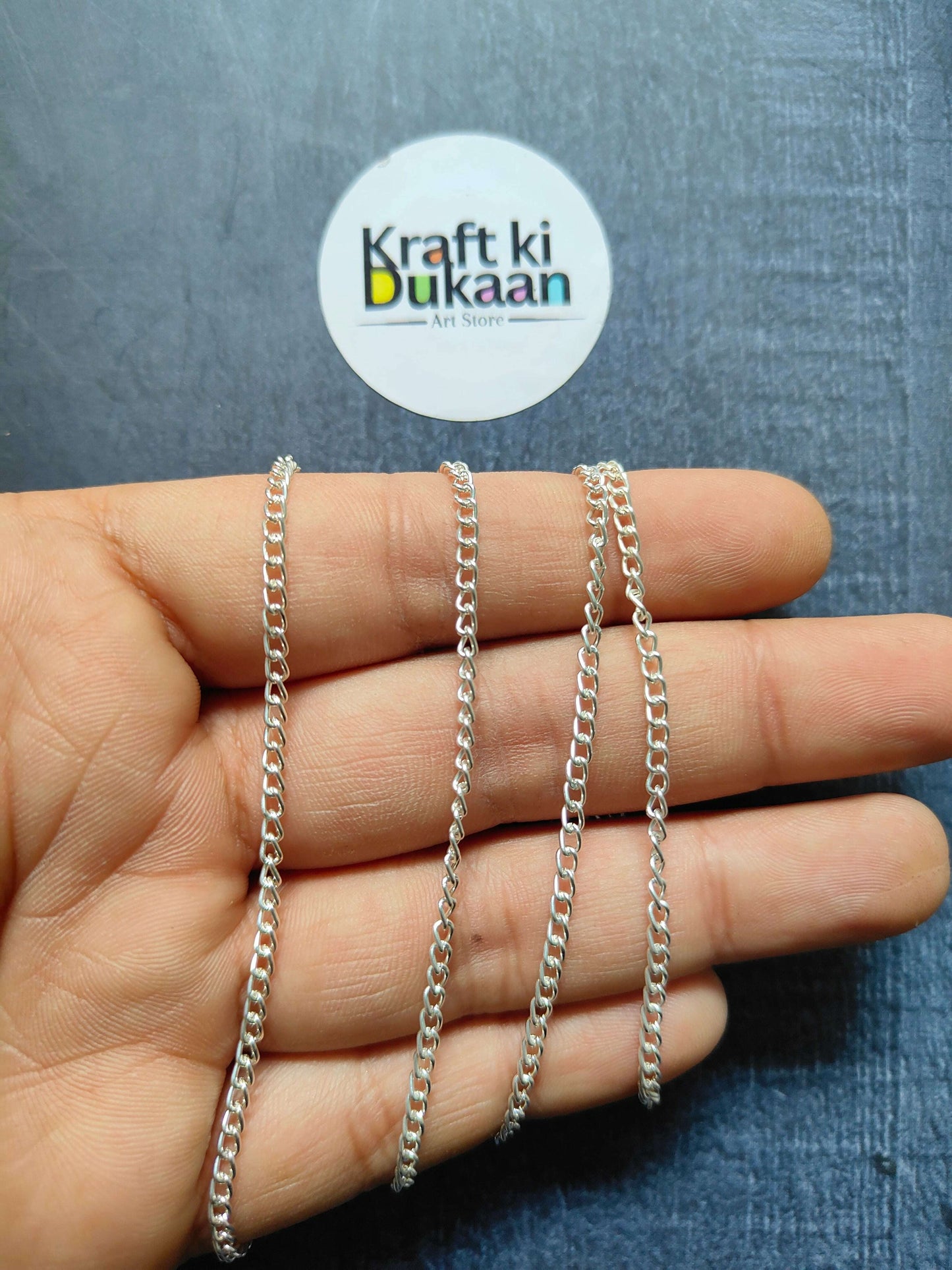 Jewellery Chain: layered silver curb-link chain bracelets on fingers