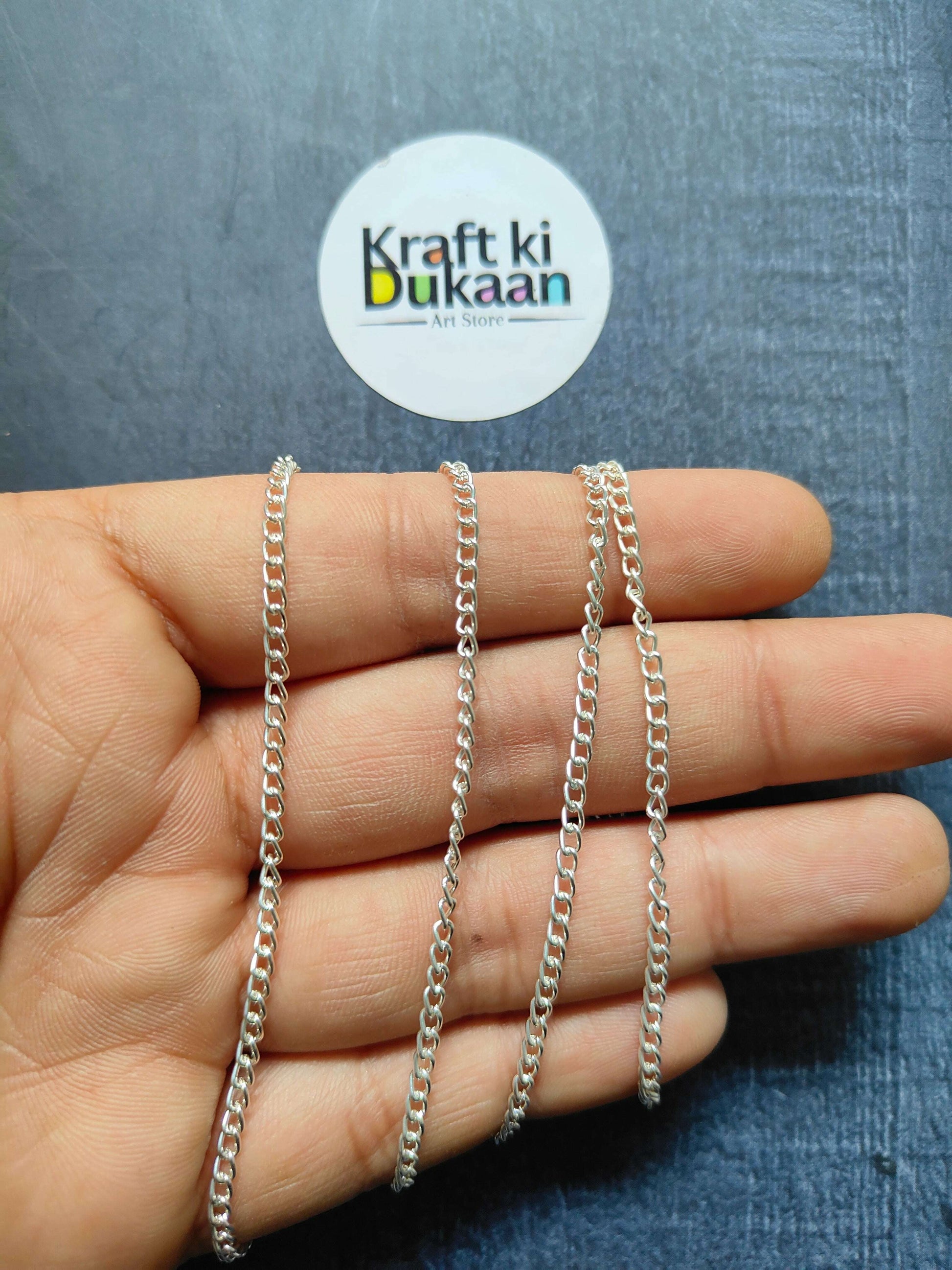 Jewellery Chain: layered silver curb-link chain bracelets on fingers