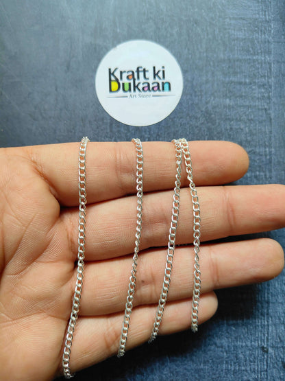 Jewellery Chain: layered silver curb-link chain bracelets on fingers