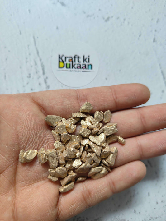 Gold nugget stones in a hand, small metallic gold chunks