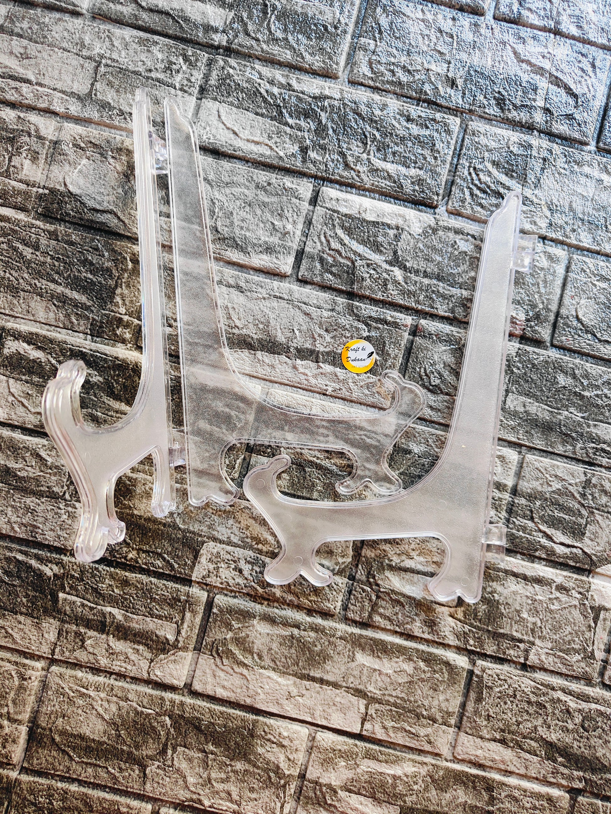 Set of clear acrylic display stands on a textured surface for showcasing art or products