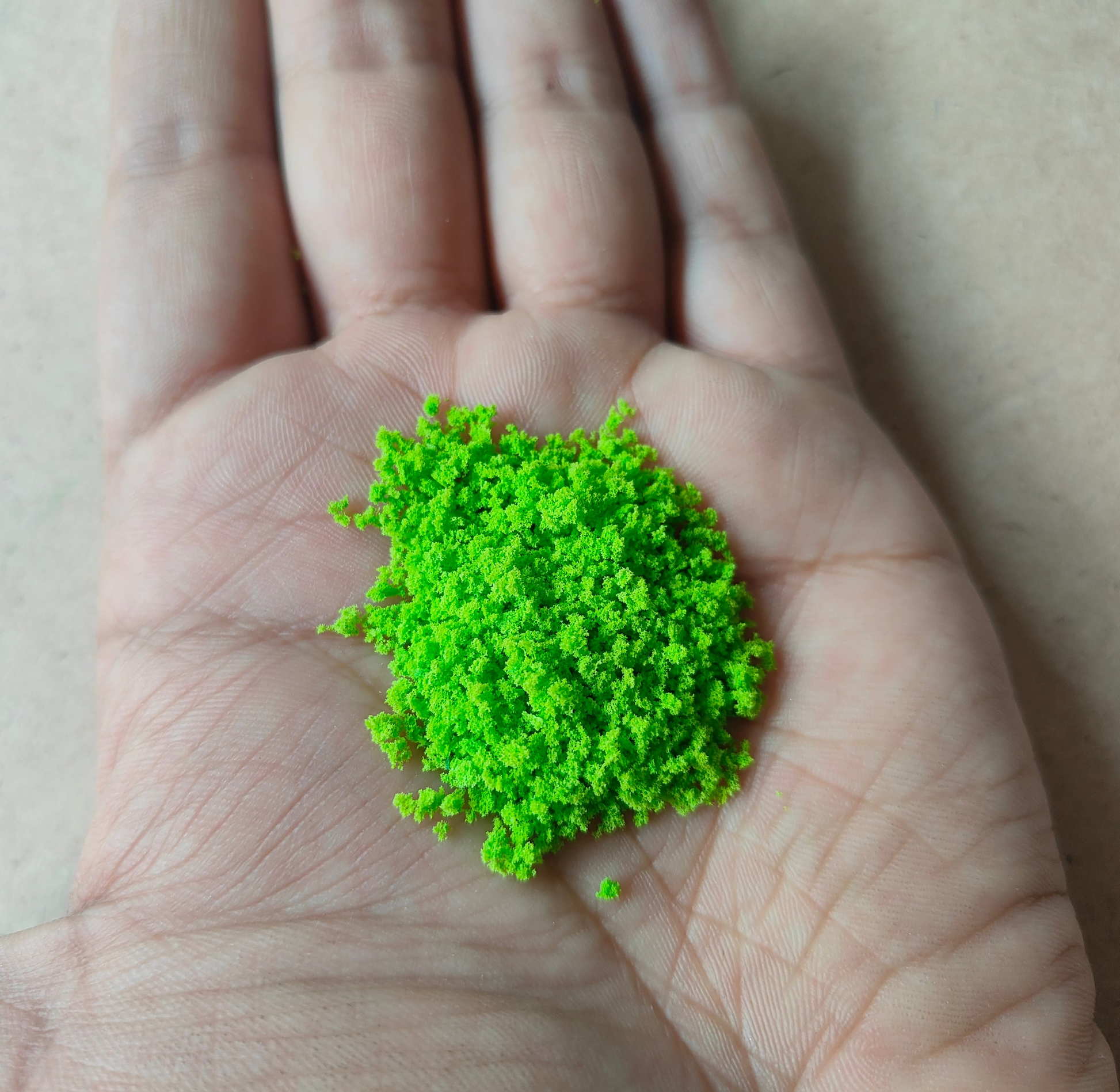 Bright green artificial moss for resin art displayed in a hand, ideal for creative projects