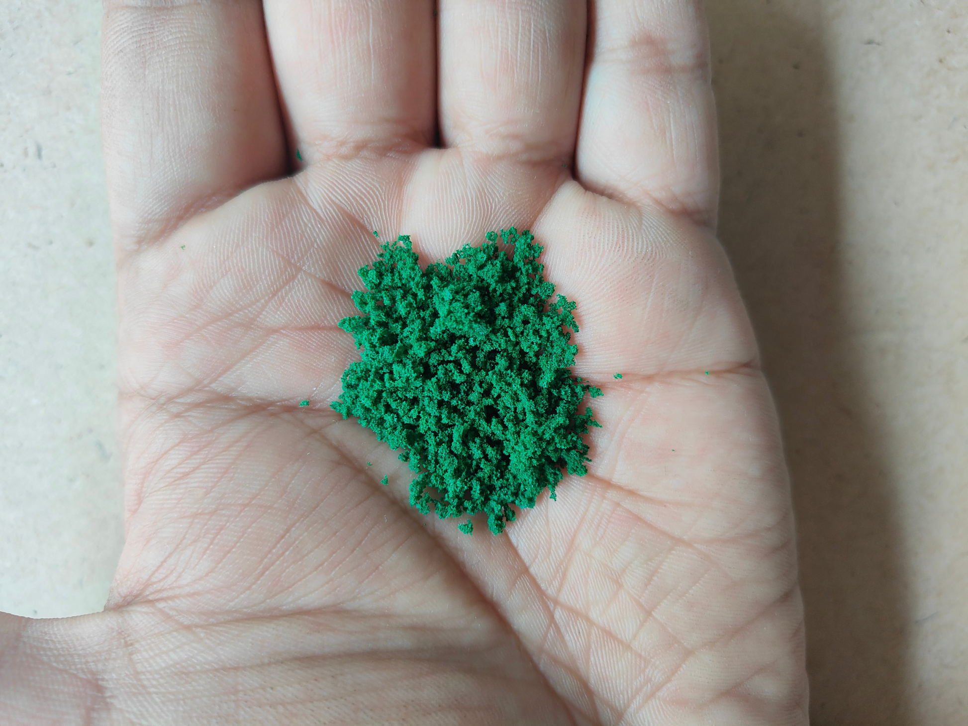 Hand holding green artificial moss for resin art, ideal for crafting and decoration