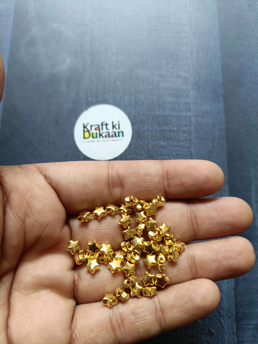 Golden star beads pack of 10GM, scattered gold star beads between fingers