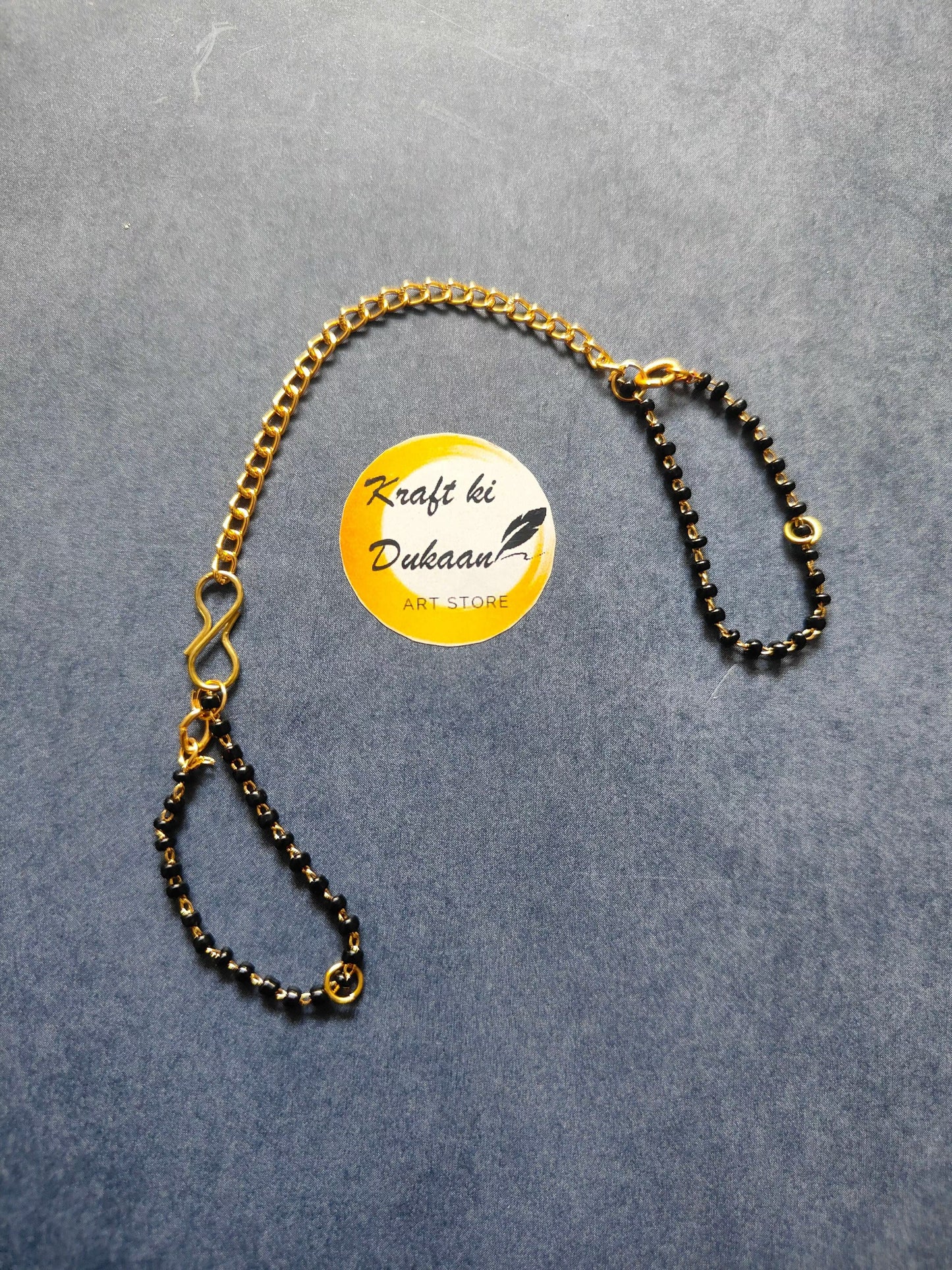 Rakhi bracelet chain with gold-tone curb links and black bead strand, ring clasp