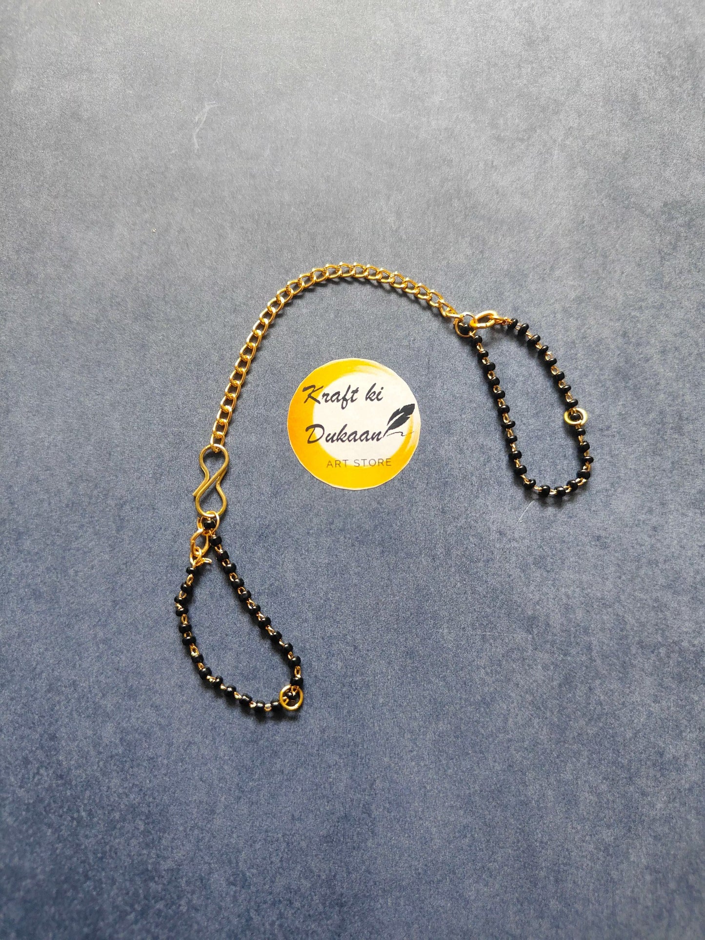 Rakhi bracelet chain with gold-tone and black bead links, adjustable loop clasp