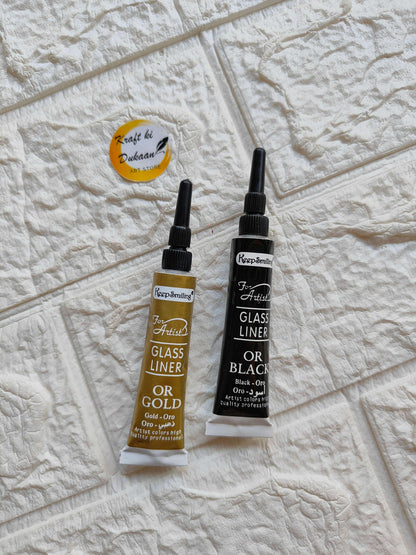 Black glass liner for resin art with a tube next to gold glass liner on a textured surface