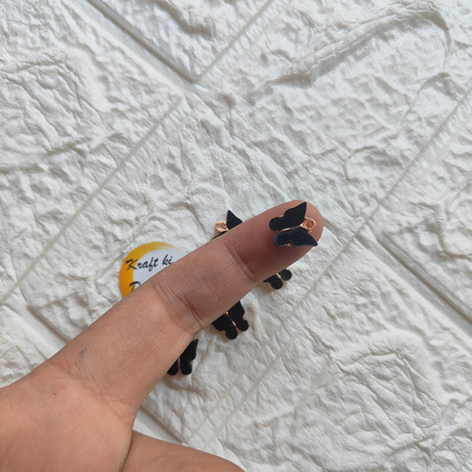 Hand holding butterfly resin pendant charms in black, perfect for jewelry making and craft projects