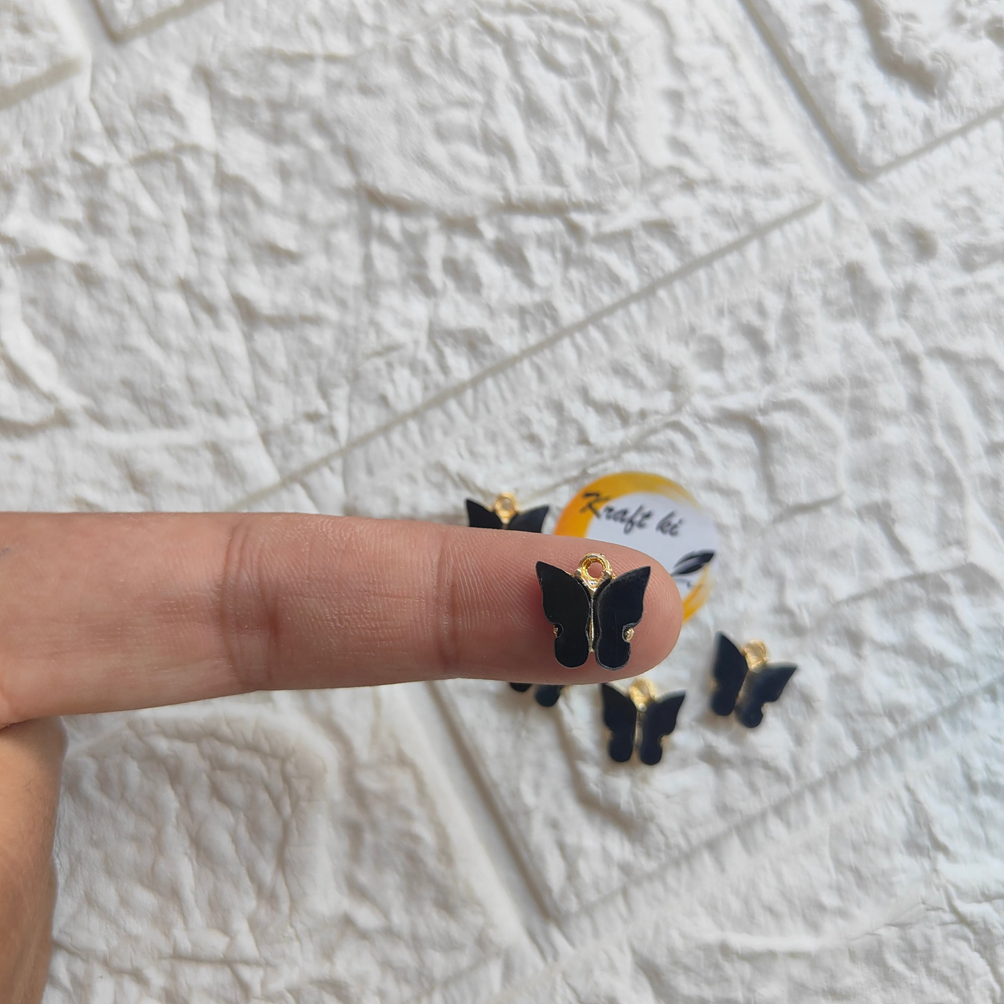 Butterfly resin pendant charms displayed on a finger for jewelry crafting inspiration