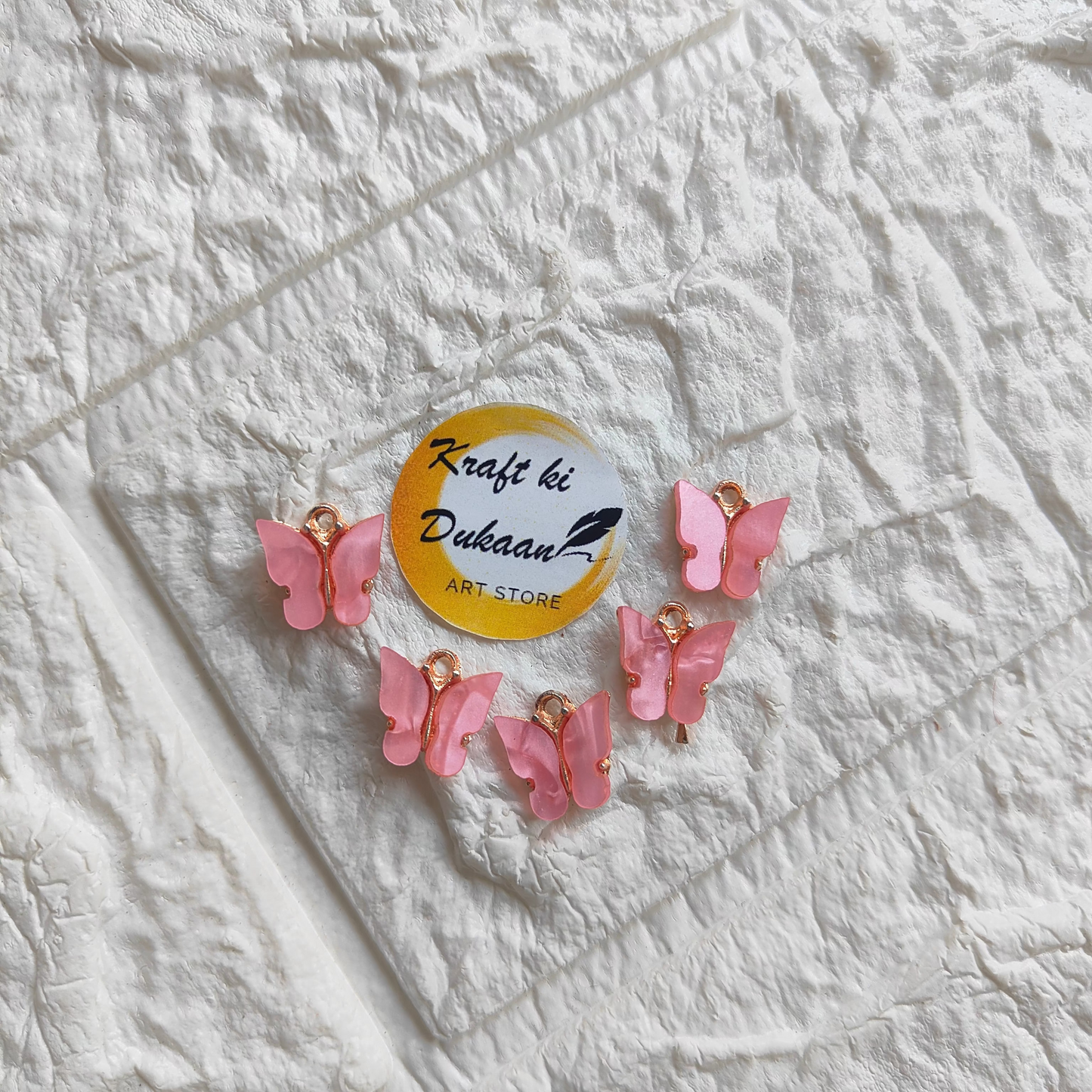 Six pink butterfly resin pendant charms on a clear background for crafting and jewelry making