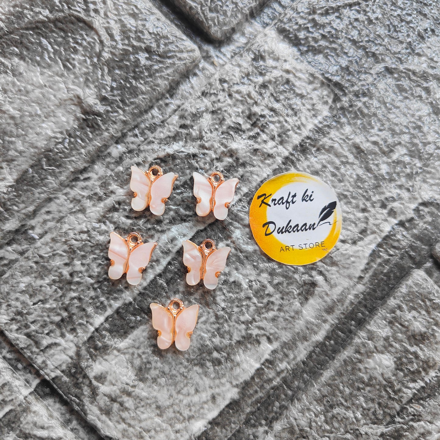 Five butterfly resin pendant charms in pastel colors, perfect for crafting and jewelry making