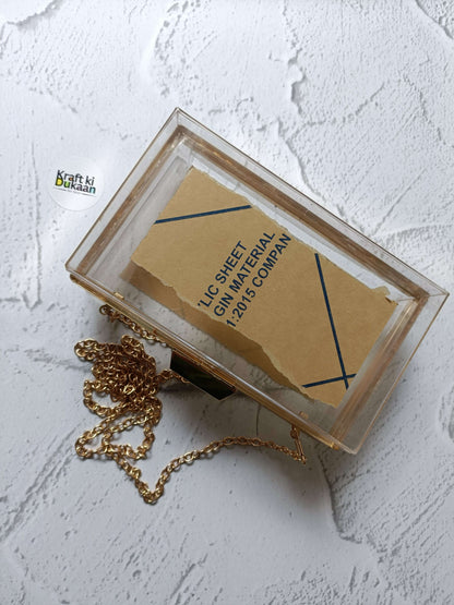 Acrylic clutch bag with gold chain and clasp; label inside the frame